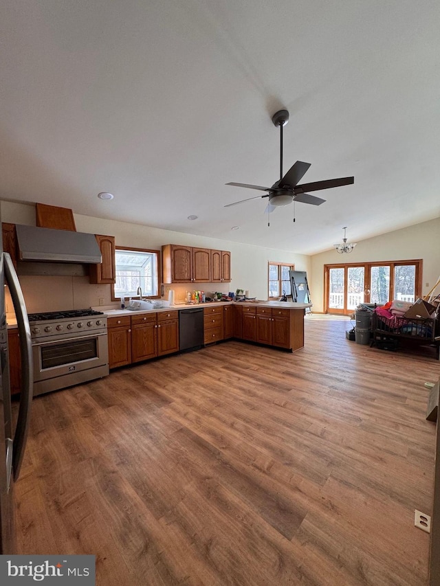 kitchen featuring hardwood / wood-style floors, sink, kitchen peninsula, stainless steel appliances, and wall chimney range hood