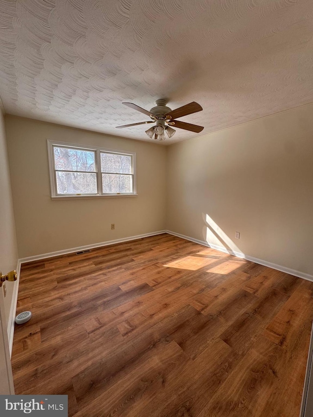 empty room with hardwood / wood-style flooring, ceiling fan, and a textured ceiling