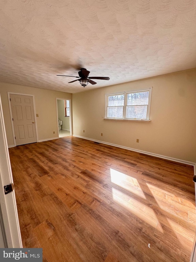 empty room featuring ceiling fan, wood-type flooring, and a textured ceiling