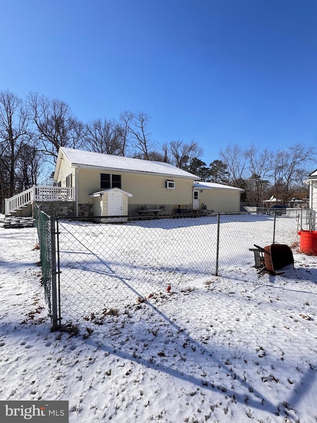 snow covered rear of property featuring a storage unit