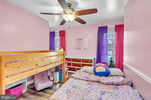 bedroom with ceiling fan, multiple windows, and hardwood / wood-style floors