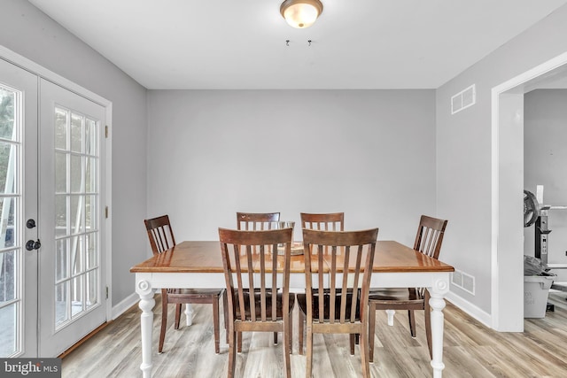 dining space with french doors and light wood-type flooring