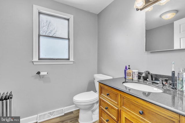 bathroom with hardwood / wood-style floors, toilet, and vanity