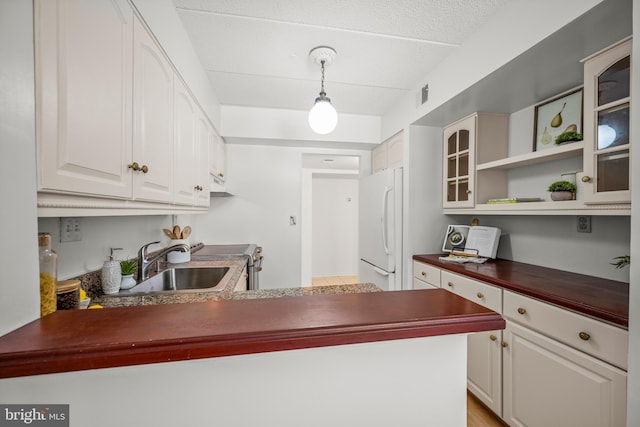 kitchen with kitchen peninsula, white cabinetry, white refrigerator, and stainless steel range oven