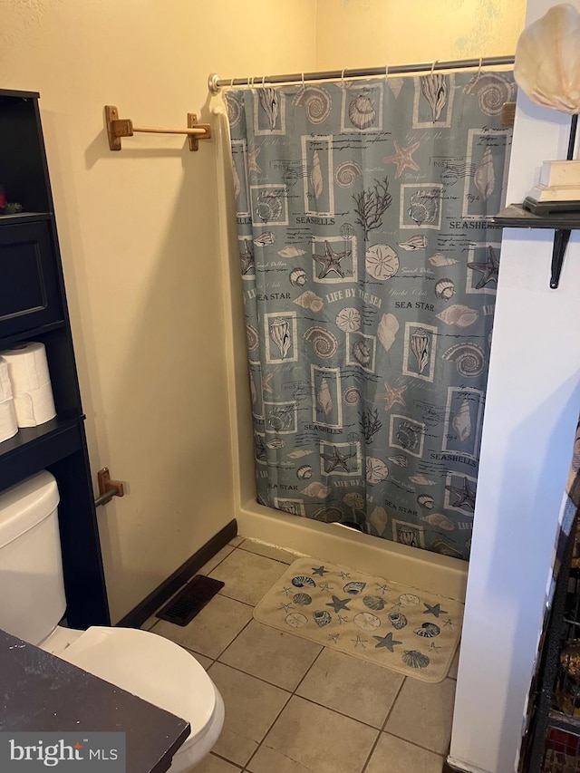 bathroom featuring a shower with curtain, toilet, and tile patterned flooring