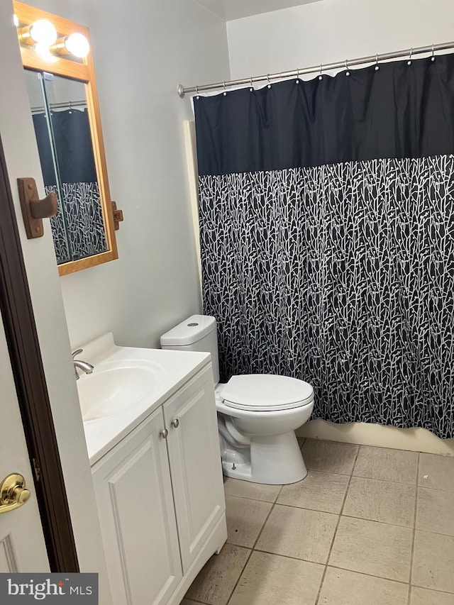 bathroom with vanity, toilet, curtained shower, and tile patterned flooring