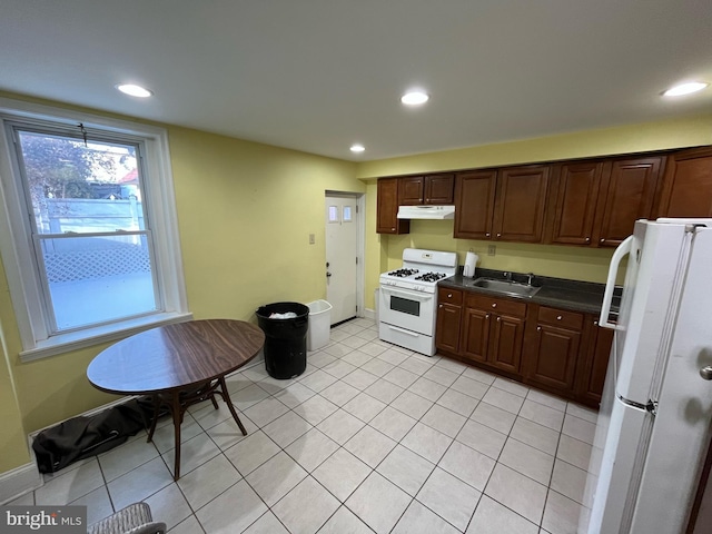 kitchen featuring sink, dark brown cabinetry, white appliances, and light tile patterned floors