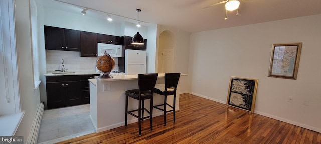 kitchen with sink, a kitchen breakfast bar, a kitchen island, white appliances, and decorative backsplash