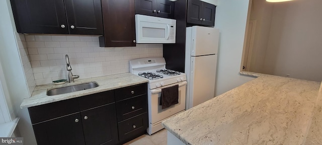 kitchen with sink, light tile patterned floors, white appliances, light stone countertops, and decorative backsplash