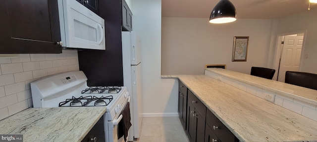 kitchen with light stone counters, tasteful backsplash, light tile patterned floors, a kitchen breakfast bar, and white appliances