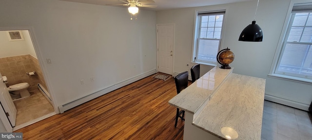 office space with dark wood-type flooring, a baseboard radiator, and ceiling fan