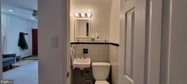 bathroom featuring sink, tile walls, and toilet