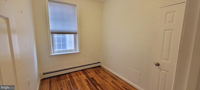 spare room with dark hardwood / wood-style flooring and a baseboard heating unit