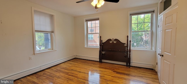 unfurnished room with a baseboard heating unit, light hardwood / wood-style floors, and ceiling fan