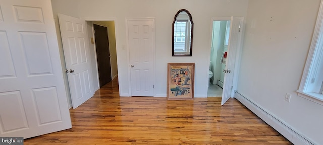 unfurnished bedroom with light hardwood / wood-style flooring and a baseboard heating unit