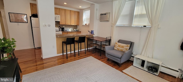 kitchen featuring a kitchen bar, tasteful backsplash, dark hardwood / wood-style flooring, a wall unit AC, and white appliances