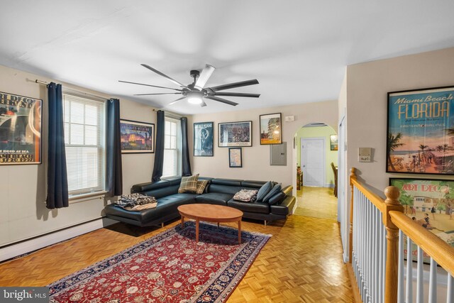 living room with baseboard heating, ceiling fan, light parquet flooring, and electric panel