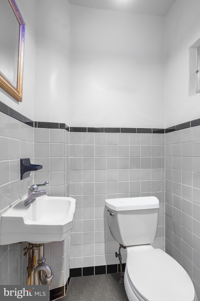 bathroom with tile walls, sink, tile patterned flooring, and toilet