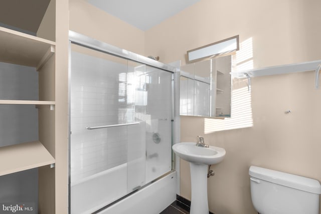 full bathroom with sink, bath / shower combo with glass door, and toilet