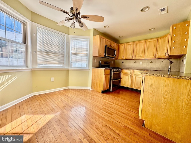 kitchen featuring light stone countertops, appliances with stainless steel finishes, decorative backsplash, light hardwood / wood-style flooring, and ceiling fan