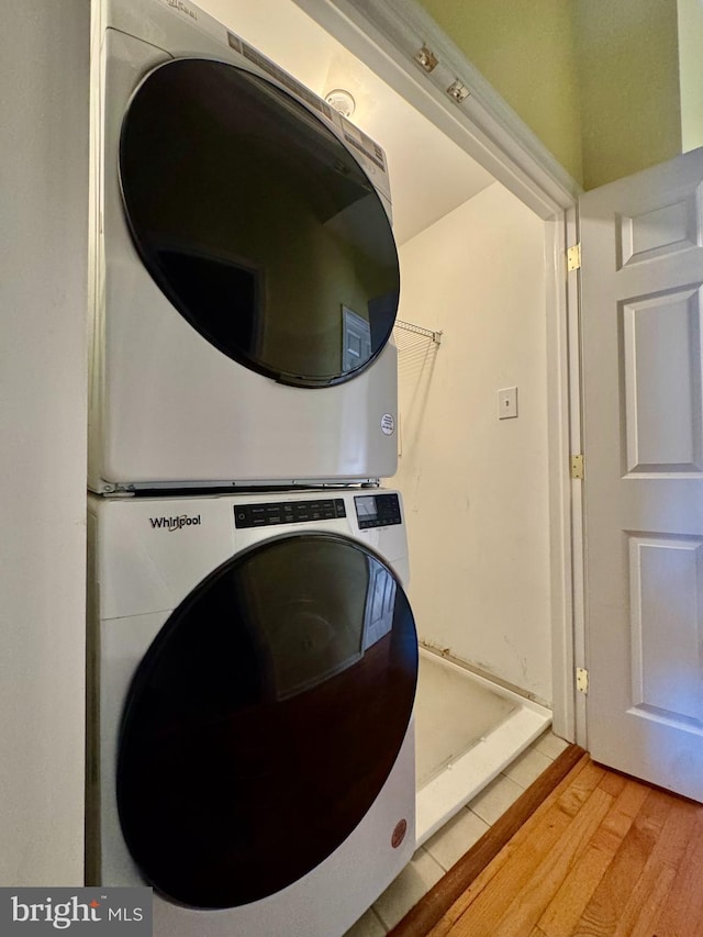 laundry room featuring hardwood / wood-style flooring and stacked washer / drying machine