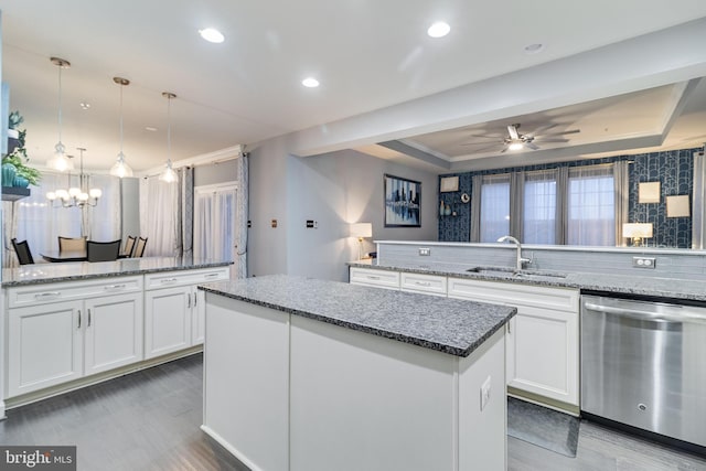 kitchen featuring stainless steel dishwasher, sink, hanging light fixtures, and white cabinets