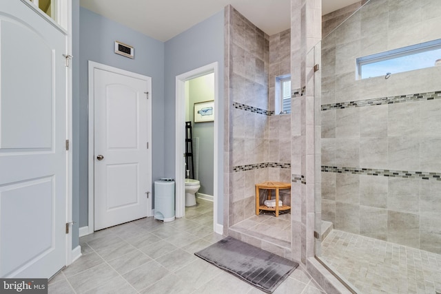 bathroom with tiled shower, tile patterned floors, and toilet