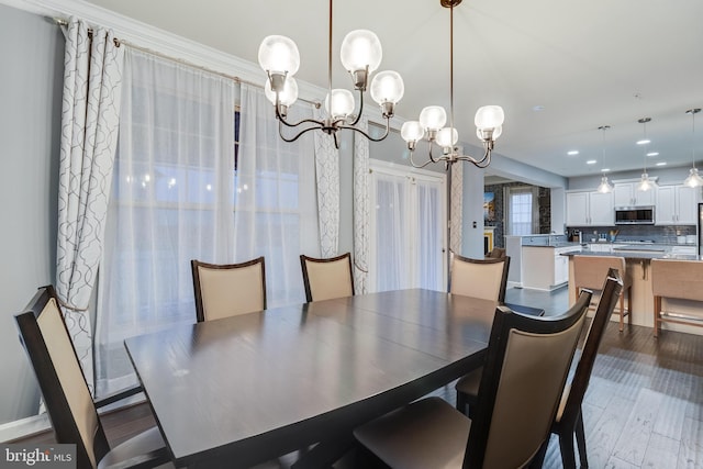 dining room featuring hardwood / wood-style flooring, ornamental molding, and a notable chandelier