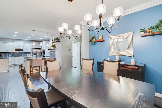 dining space with crown molding, hardwood / wood-style floors, and a notable chandelier