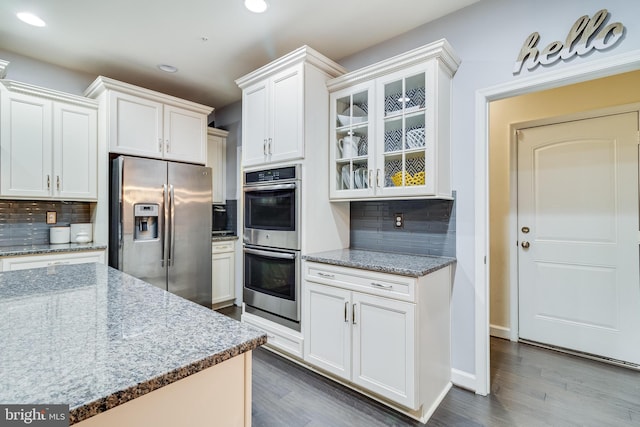 kitchen featuring white cabinetry, tasteful backsplash, light stone countertops, and appliances with stainless steel finishes