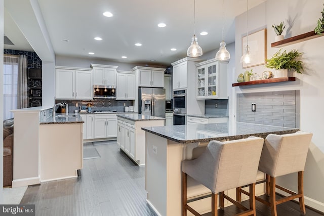 kitchen with sink, a breakfast bar area, white cabinetry, stainless steel appliances, and kitchen peninsula