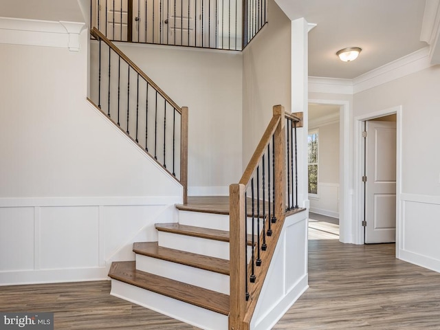 stairway with hardwood / wood-style floors and crown molding