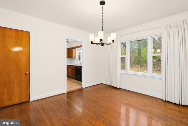 unfurnished dining area with a notable chandelier and wood-type flooring