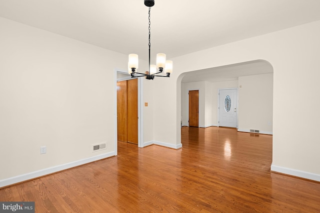 unfurnished dining area with hardwood / wood-style flooring and a notable chandelier