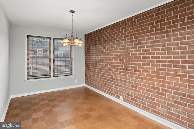 spare room featuring parquet flooring, brick wall, and an inviting chandelier