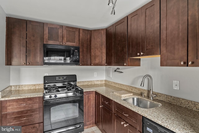 kitchen featuring sink, light tile patterned floors, light stone countertops, track lighting, and black appliances