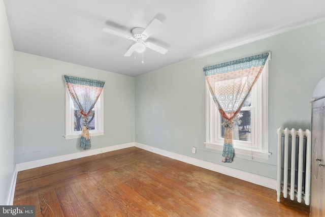 empty room with ceiling fan, radiator heating unit, and wood-type flooring