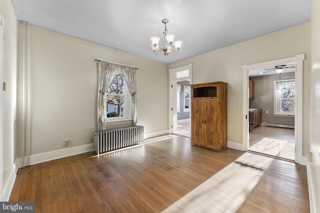 unfurnished room with an inviting chandelier, a baseboard radiator, radiator heating unit, and light wood-type flooring