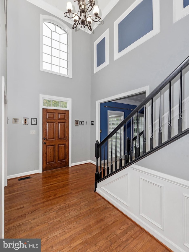 entrance foyer with a towering ceiling, a chandelier, and hardwood / wood-style flooring