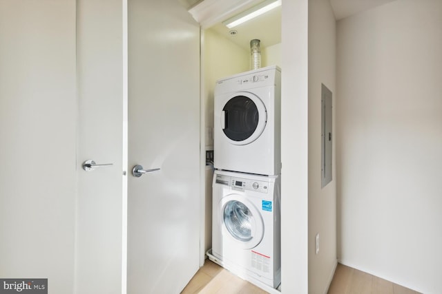 clothes washing area with stacked washer / dryer, electric panel, and light hardwood / wood-style floors