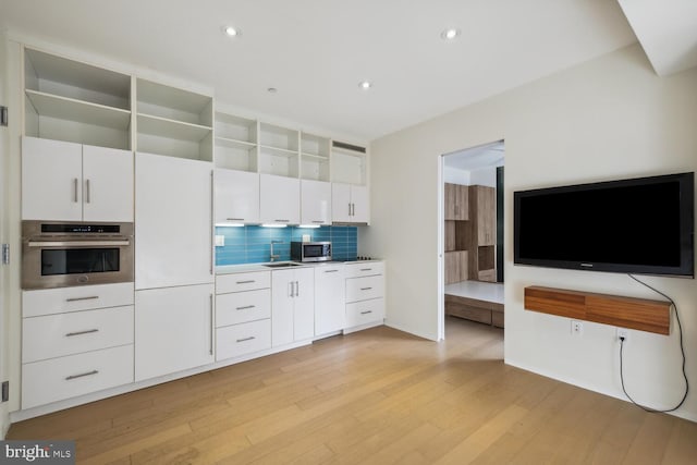 kitchen featuring tasteful backsplash, white cabinetry, light hardwood / wood-style floors, and appliances with stainless steel finishes