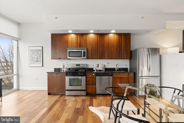 kitchen with stainless steel appliances, a healthy amount of sunlight, sink, and light hardwood / wood-style floors