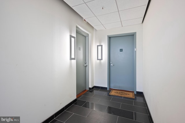 corridor with a paneled ceiling and dark tile patterned floors