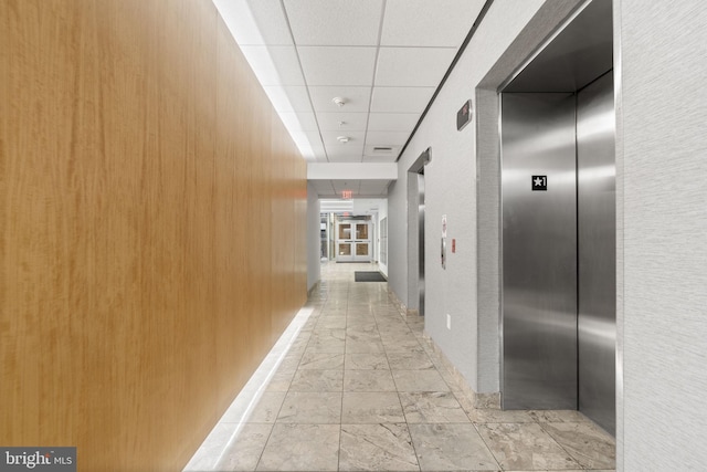 hallway with elevator and a paneled ceiling