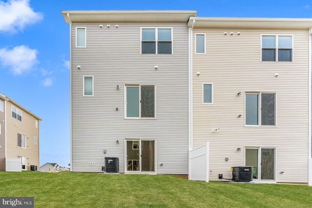 back of property with central AC unit and a lawn