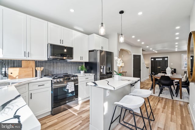 kitchen with appliances with stainless steel finishes, sink, decorative light fixtures, tasteful backsplash, and white cabinetry