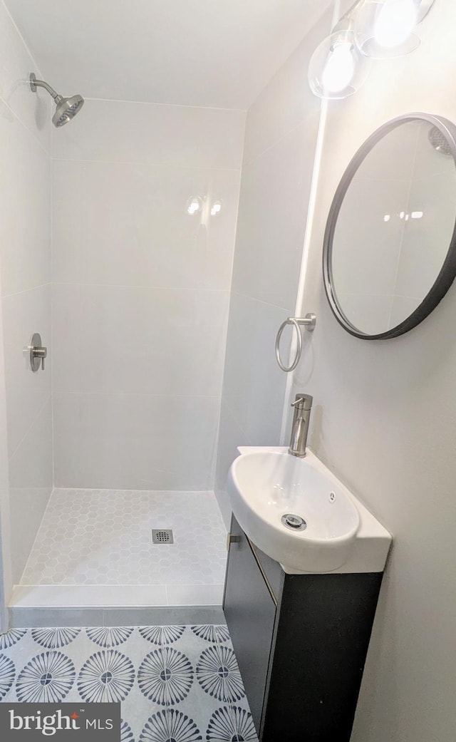 bathroom with vanity, a tile shower, and tile patterned flooring