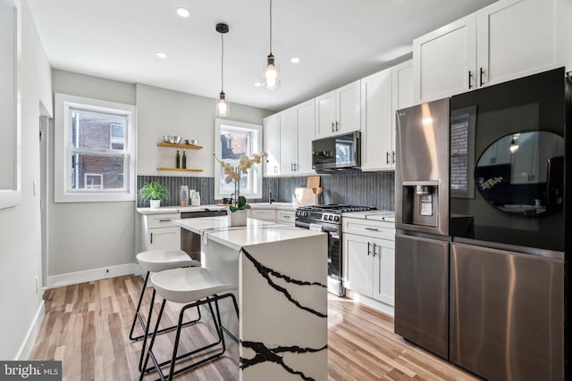 kitchen with a center island, tasteful backsplash, white cabinets, pendant lighting, and stainless steel appliances