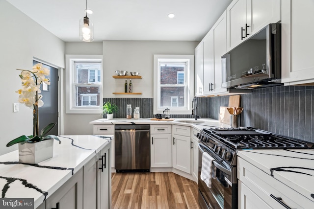 kitchen with white cabinets, stainless steel appliances, a wealth of natural light, and hanging light fixtures