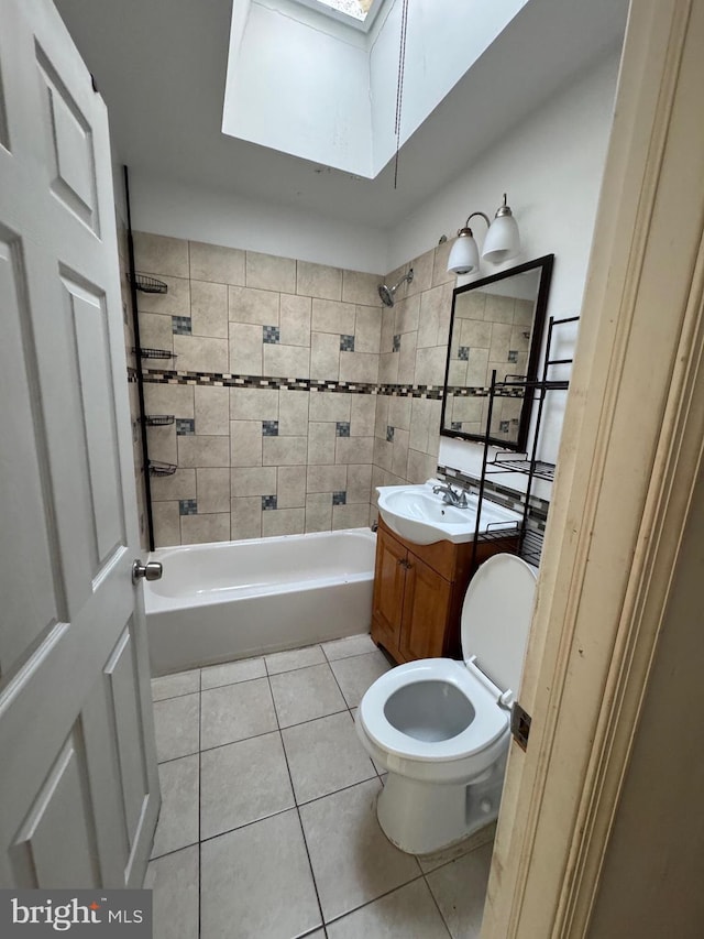 full bathroom featuring toilet, a skylight, tile patterned flooring, vanity, and tiled shower / bath